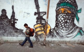 Palestinian boy passing by a grafitti as he walks to school at Jabalia area, northern Gaza Strip