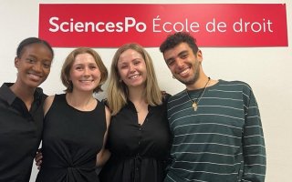 Four people standing in front of a banner reading SciencesPo Ecole de droit