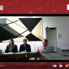 Screenshot of panel discussion, showing three people sitting at a desk